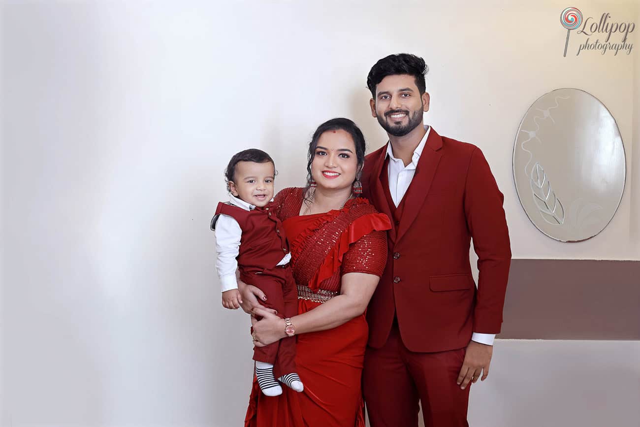 Kian with his parents, all dressed in red, during a warm family birthday photo session by Lollipop Photography in Chennai