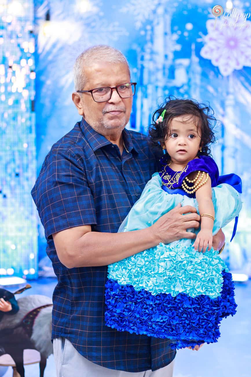 Pranika and her grandfather share a special moment, dressed in a blue gown, captured by Lollipop Photography at her birthday celebration in Coimbatore