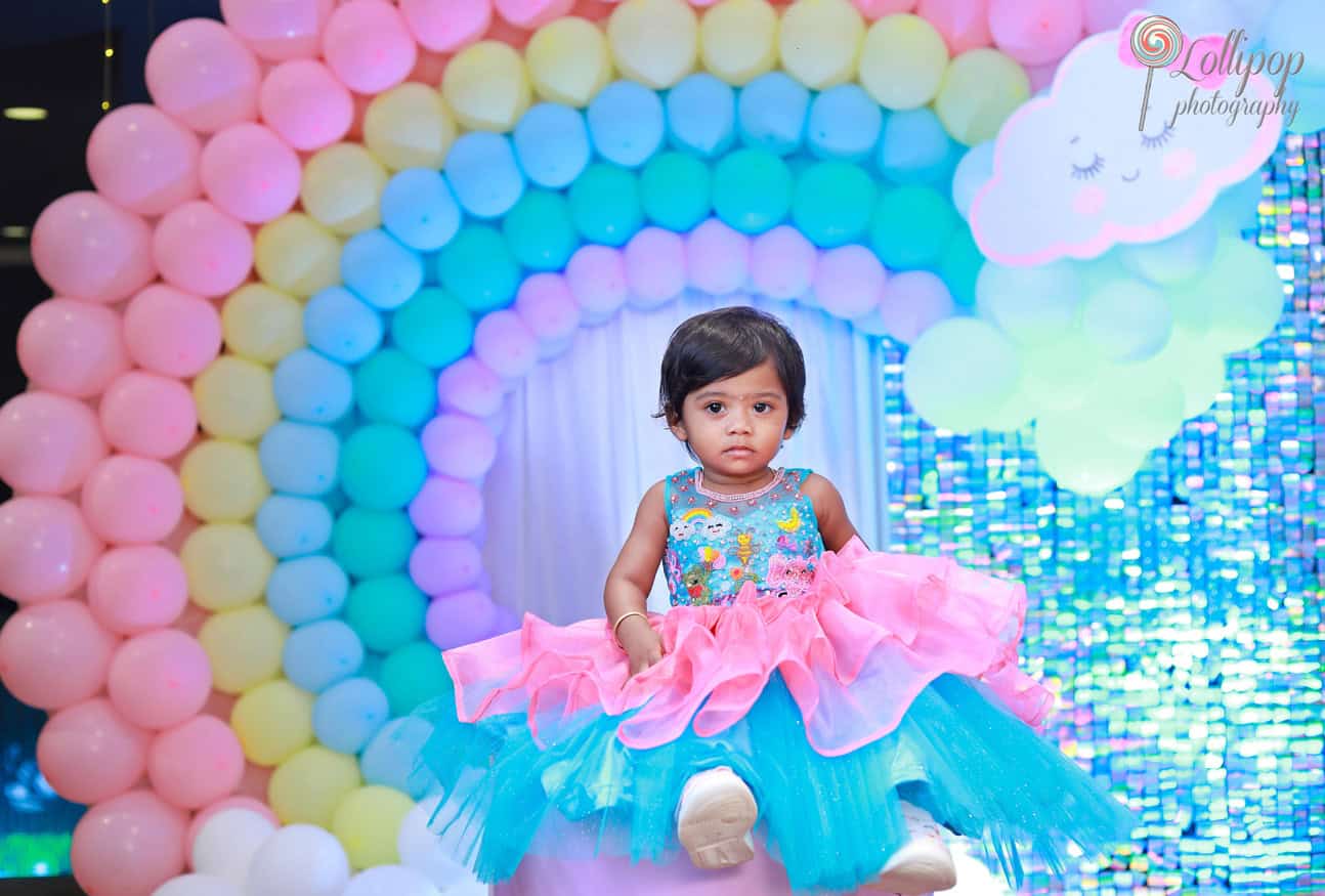 Kanali poses in front of a vibrant rainbow balloon backdrop at her birthday party, skillfully photographed by Lollipop Photography in Chennai