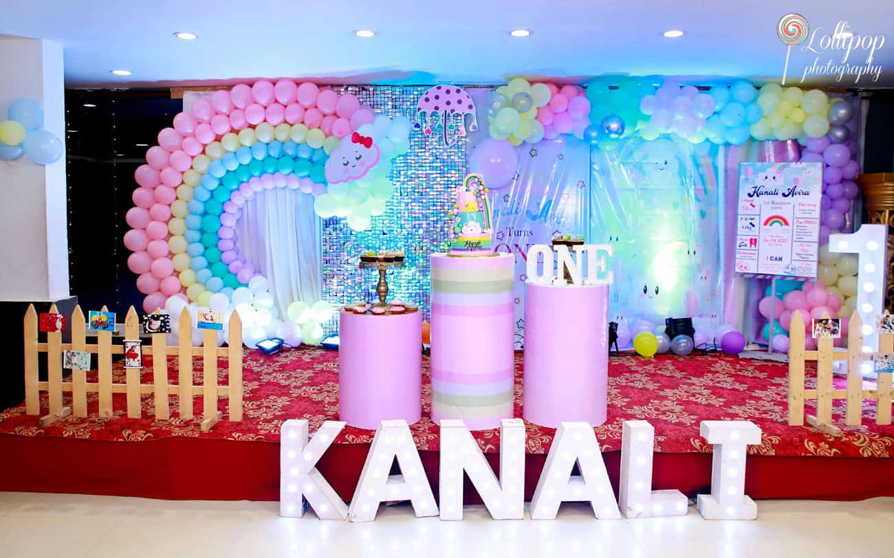 Colorful rainbow balloon arch and birthday setup with ‘Kanali’ illuminated letters at the front, designed by Lollipop Photography