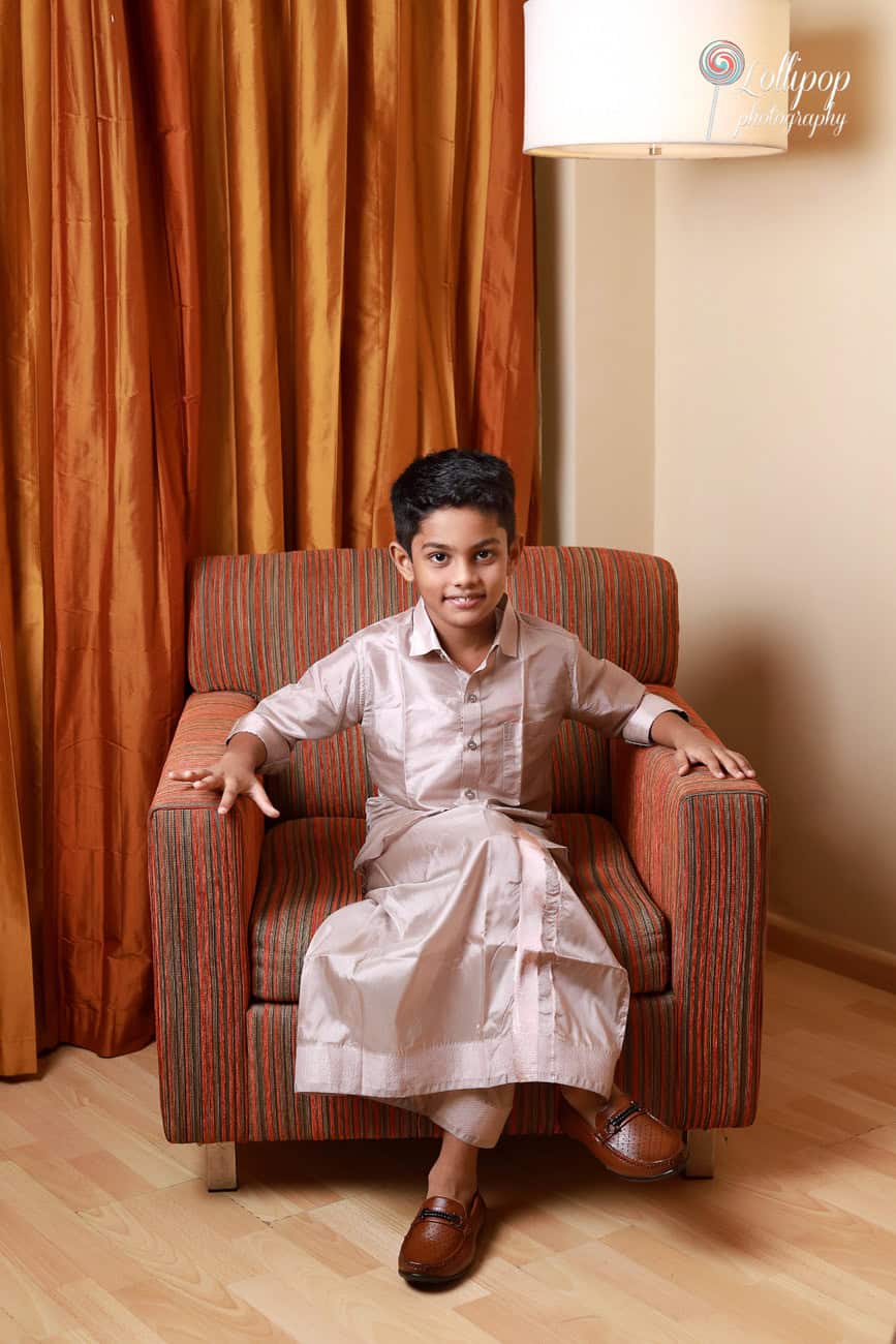 Aryan’s elder brother posing in traditional attire, seated in an armchair during Aryan’s birthday celebration in Chennai, captured by Lollipop Photography