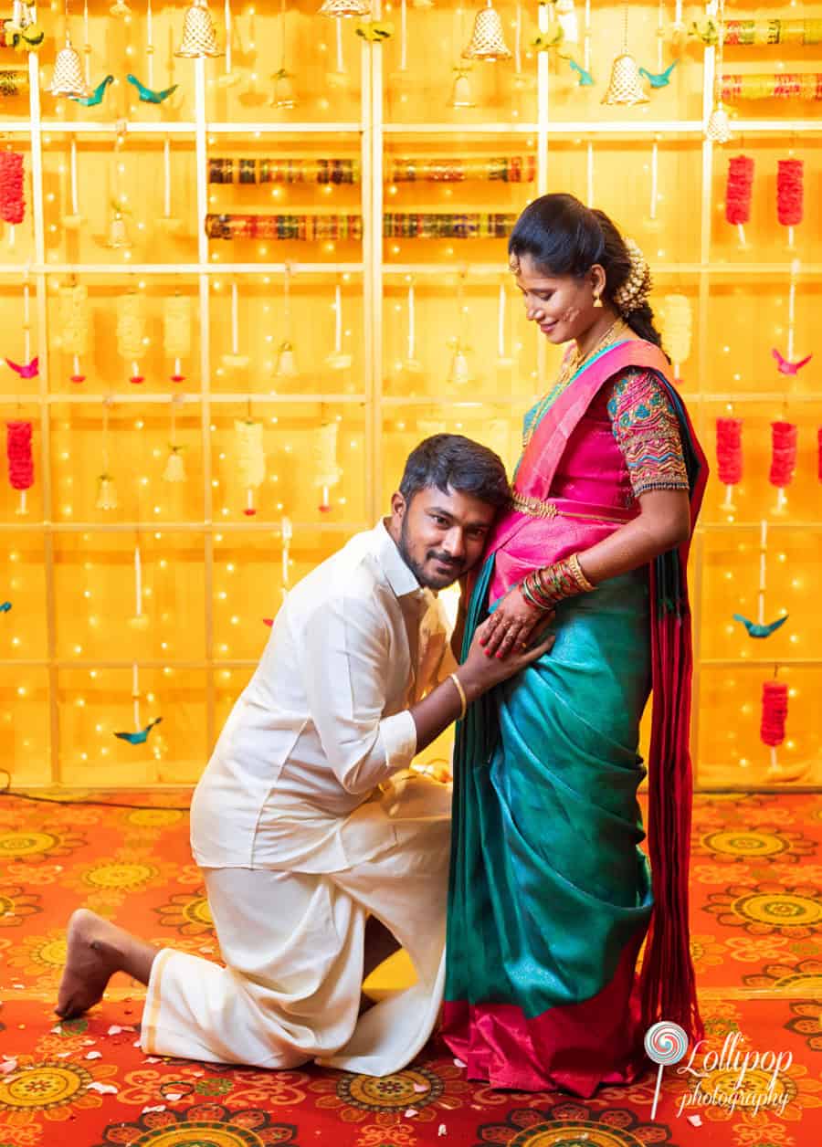 Naveen Kumar kneeling and adoring Arthi's baby bump, celebrating their love and anticipation during their baby shower in Chennai, captured by Lollipop Photography