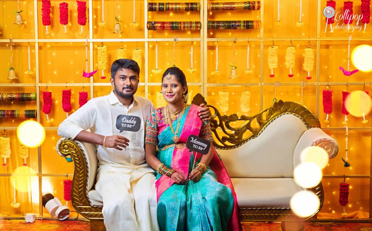 Arthi and Naveen Kumar holding 'Mommy to Be' and 'Daddy to Be' signs during their baby shower celebration in Chennai, captured by Lollipop Photography