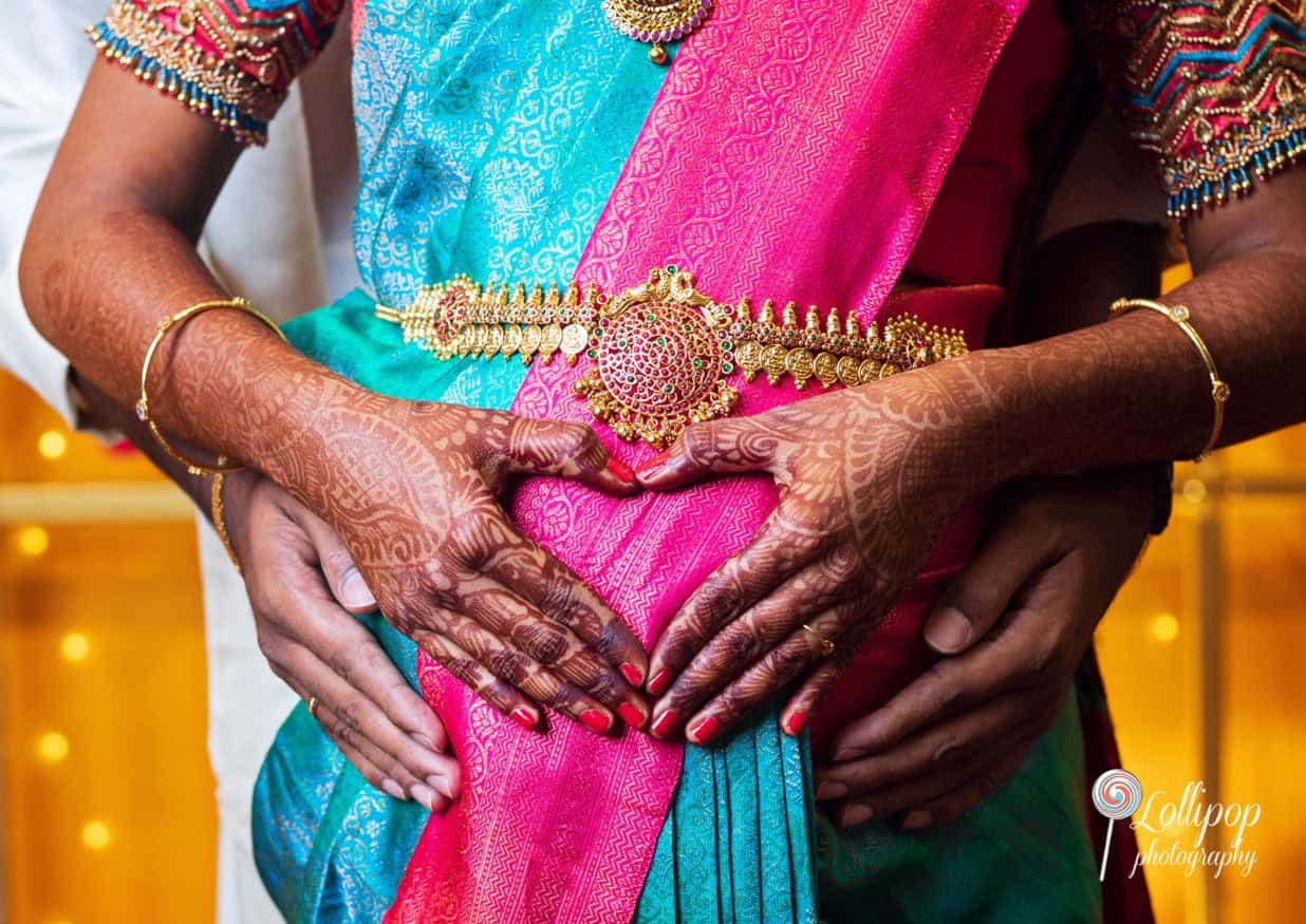 Close-up of Arthi and Naveen Kumar making a heart gesture over the baby bump, a special moment from their baby shower in Chennai