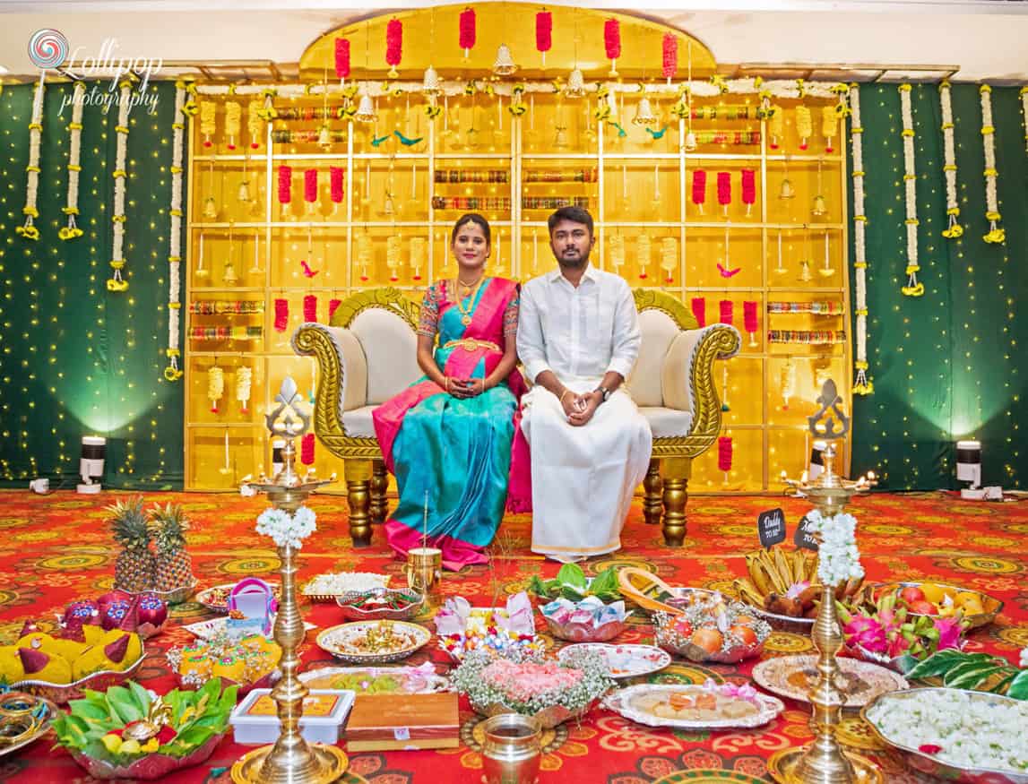 Arthi and Naveen Kumar seated for a traditional baby shower ceremony setup with cultural decor in Chennai, captured by Lollipop Photography