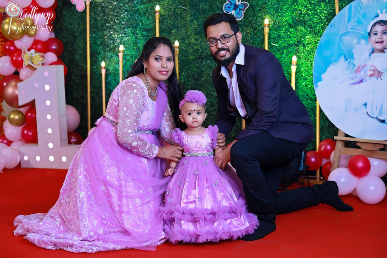 A family of three enjoying a butterfly-themed birthday celebration with vibrant decorations and custom backdrops. Birthday photoshoot by Lollipop Photography, Chennai.