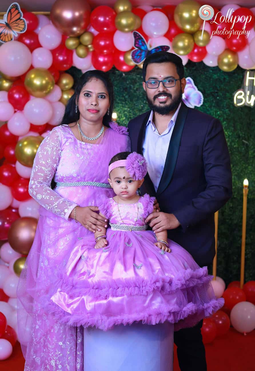 A family celebrating their daughter's birthday with a butterfly-themed backdrop, dressed in coordinated outfits. Birthday photoshoot by Lollipop Photography in Chennai