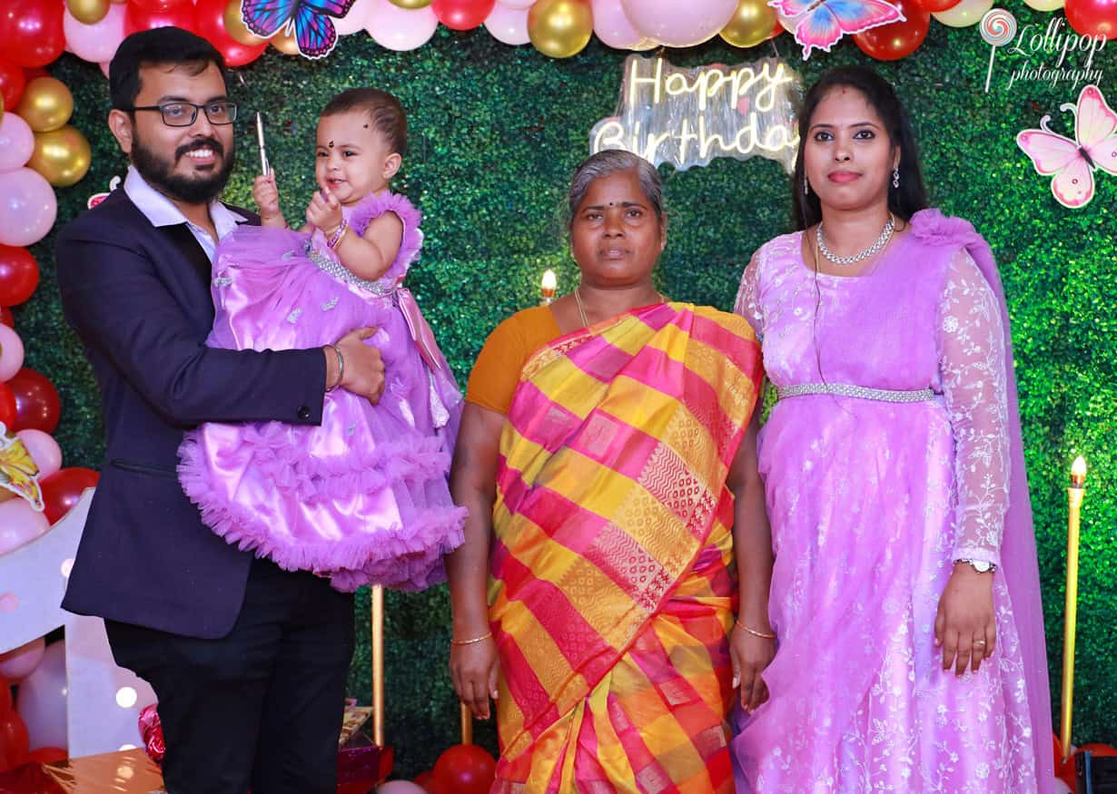 A family photo with the baby girl, parents, and grandmother at a butterfly-themed birthday celebration. Captured by Lollipop Photography, Chennai.