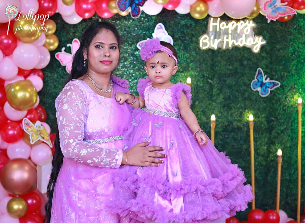 A family celebrating their baby's birthday with a butterfly-themed decor and colorful balloon arrangements, captured by Lollipop Photography in Chennai