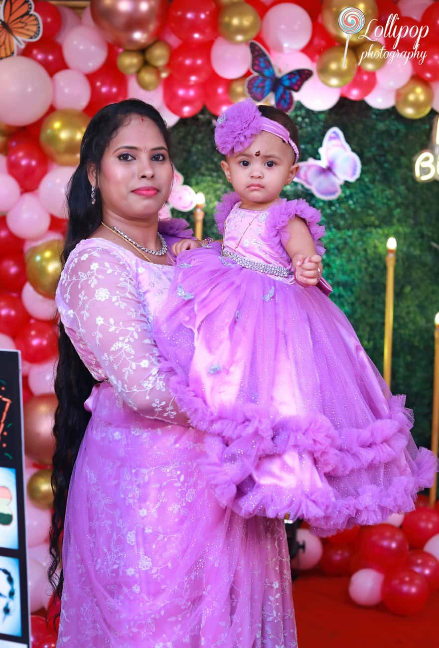 A mother and her baby girl dressed in matching purple outfits at a butterfly-themed birthday celebration. Captured by Lollipop Photography, Chennai