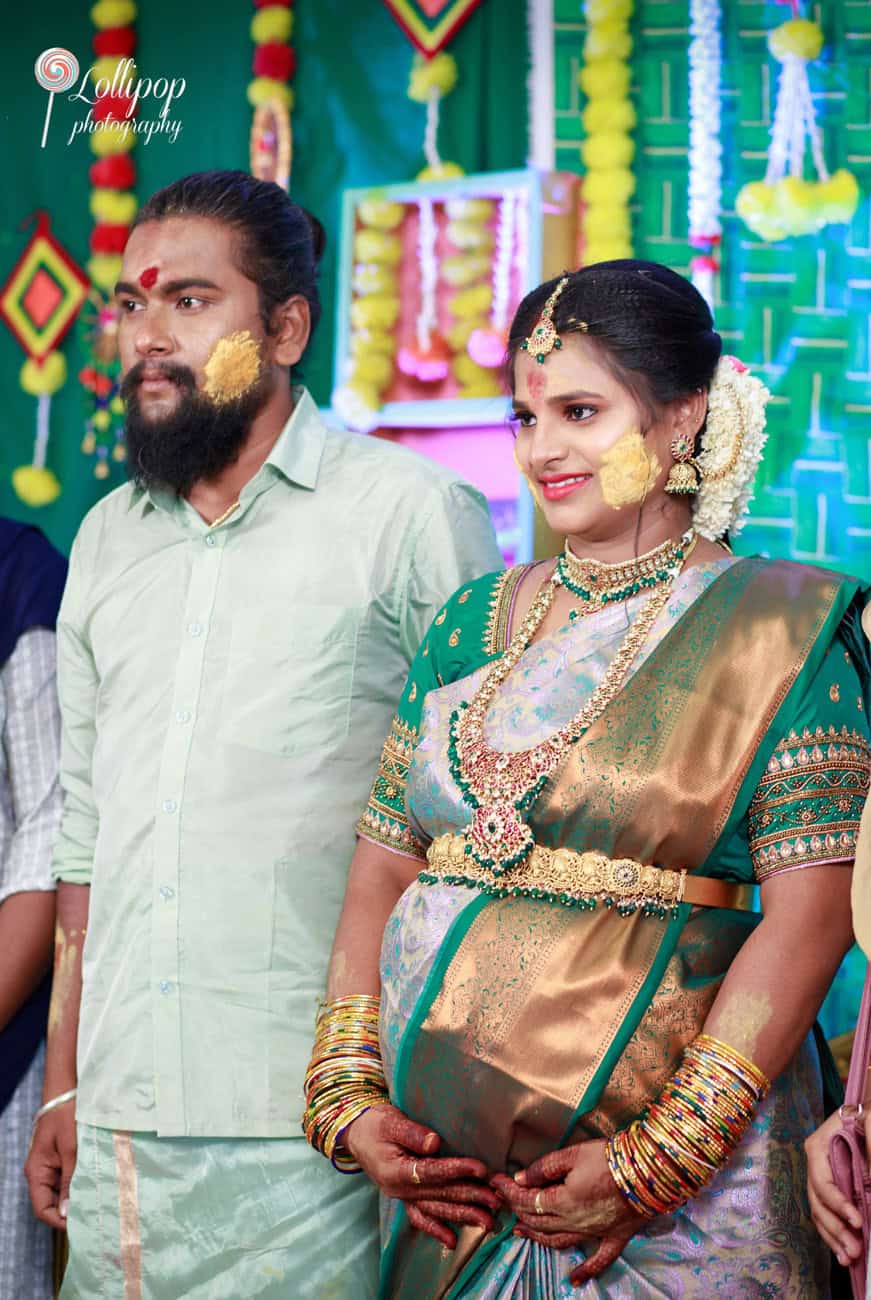 A candid smile shared by Sharmila at her baby shower in Coimbatore, beautifully adorned in floral garlands and traditional jewelry.