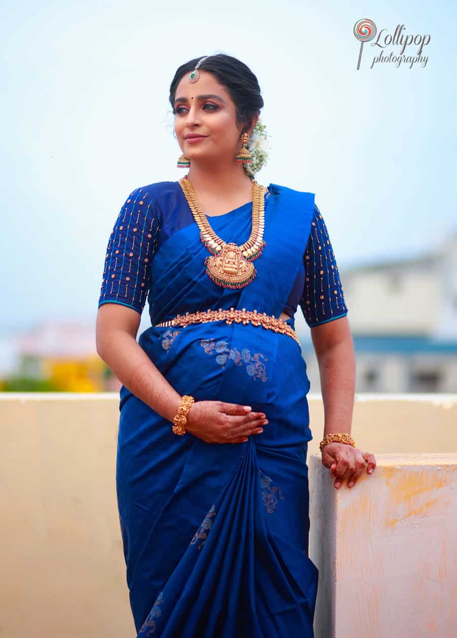 A serene mom-to-be dressed in a blue saree, cradling her baby bump during her baby shower photoshoot in Coimbatore by Lollipop Photography