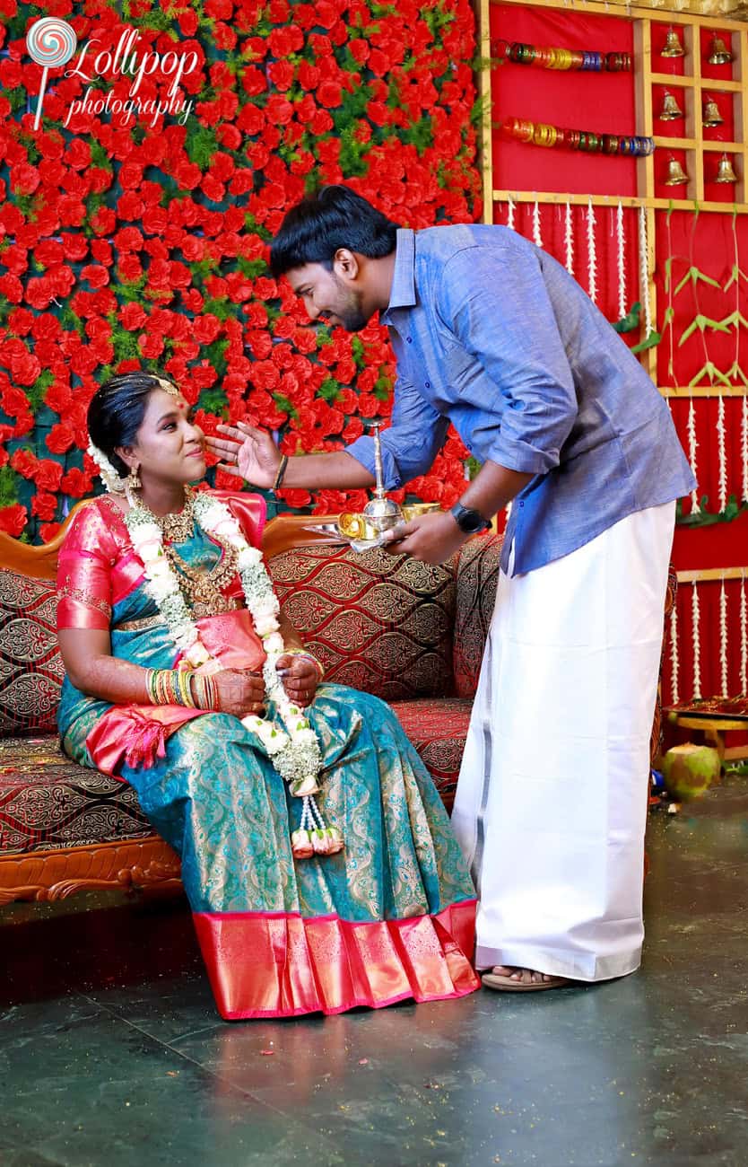 The groom gently applies a traditional ritual to the bride’s face, symbolizing love and blessing, during the baby shower ceremony