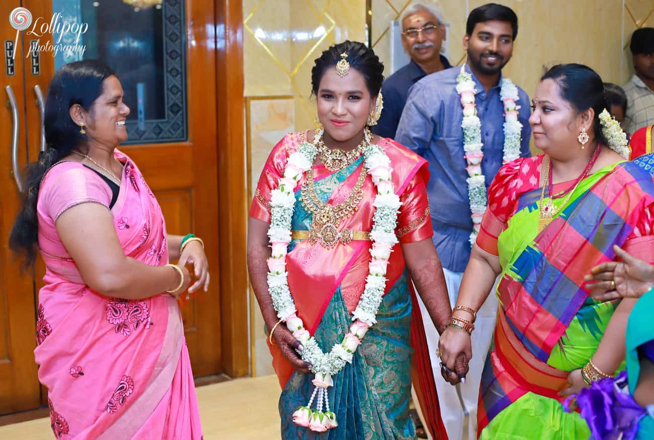 An expecting mother, surrounded by family members, shares a joyful moment as they celebrate her baby shower, documented by Lollipop Photography in Chennai