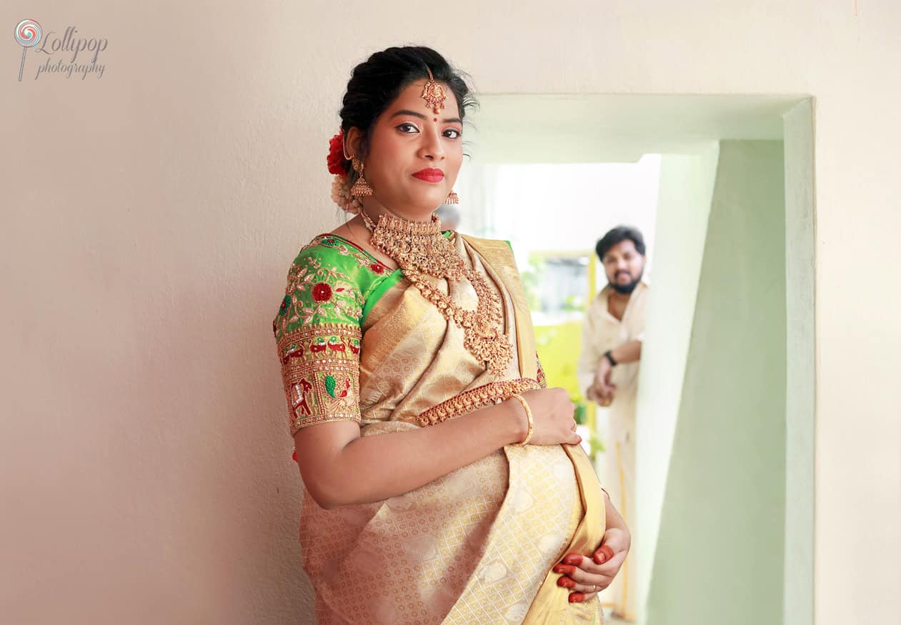 Anitha's husband lovingly watches her from afar, capturing the essence of love and anticipation during their baby shower celebration in Coimbatore