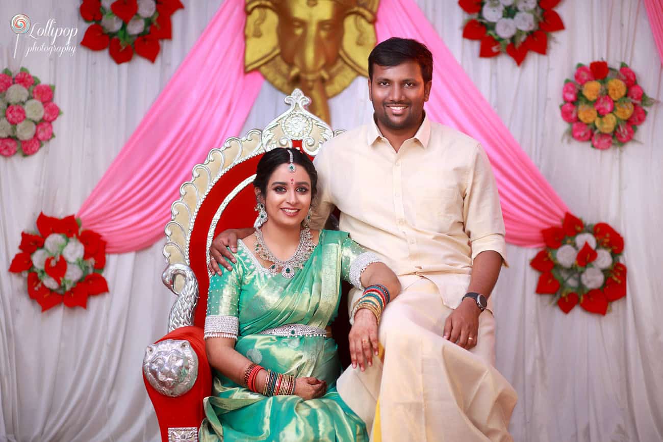 Radiant mom-to-be Pavithra sits on a ceremonial throne in her green saree, embraced by her husband, celebrating their baby shower in Coimbatore.