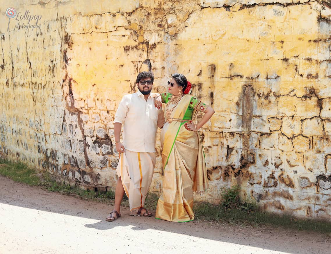 Anitha and her husband share a stylish moment against a rustic wall backdrop, adding charm to their baby shower photoshoot in Coimbatore.