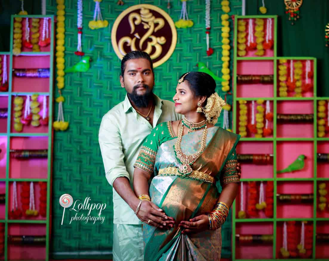 Sharmila shares a loving look with her husband amidst the colorful baby shower decorations in Coimbatore, beautifully captured by Lollipop Photography.