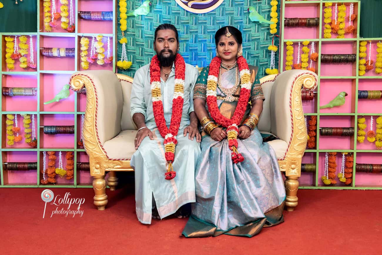 Sharmila and her husband seated on the baby shower stage, surrounded by bright festive decor, captured during their special day by Lollipop Photography in Coimbatore.